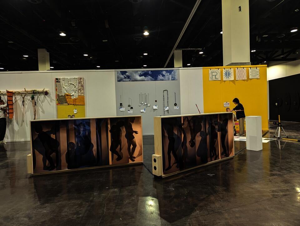 two large horizonal light boxes lit on both sides. one side has a silhouetted body making repeated gestures and the other in a person laying in a bed