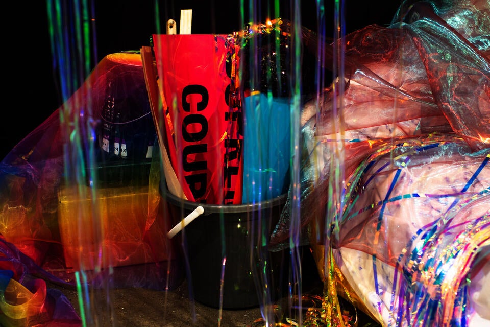 tiridescent sheer Fuschia with blue organza, iridescent vinyl party streamers, photo documents and Instagram stories printed on paper, artist tapes, 'Cruising Utopia' by José Esteban Muñoz 'All About Love: New Visions' by bell hooks, and wooden board.