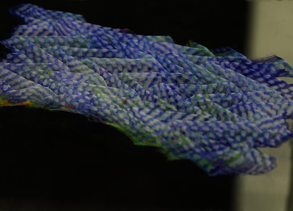 Detail shot of knitted technical structures sampler swatch on acrylic pedestal