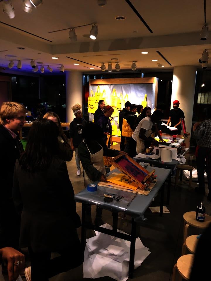 Crowd of teenagers in front of tables with screenprinting stations 