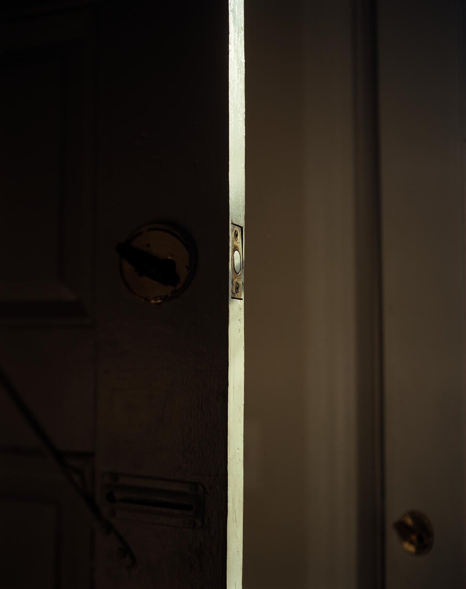 Photograph of two white doors. The open door on the left's lock latch is angled left. In the bottom right is the the second door's lock. it is also angled left.