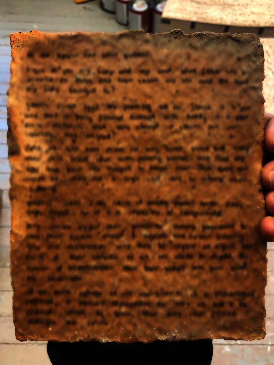 Back of tablet: writing printed in uv ink has been blurred out to hide the curse from human eyes, protecting its efficacy 