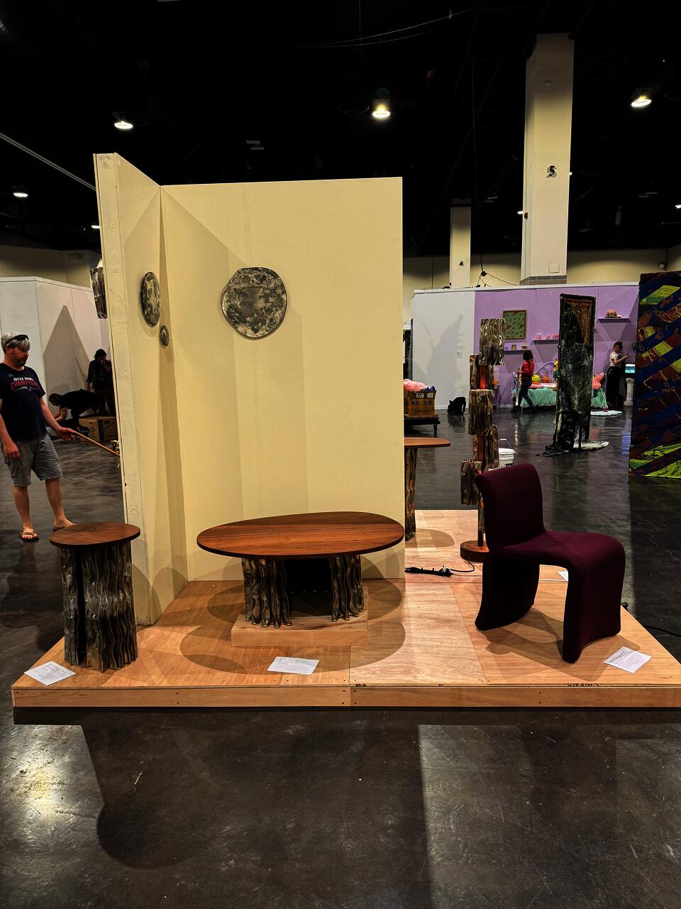 A modern furniture collection includes a coffee table, console table, pedestal table, and two floor lamps. The tables have an aluminum base and walnut tops. The floor lamps display decorative aluminum shades and central walnut stands.