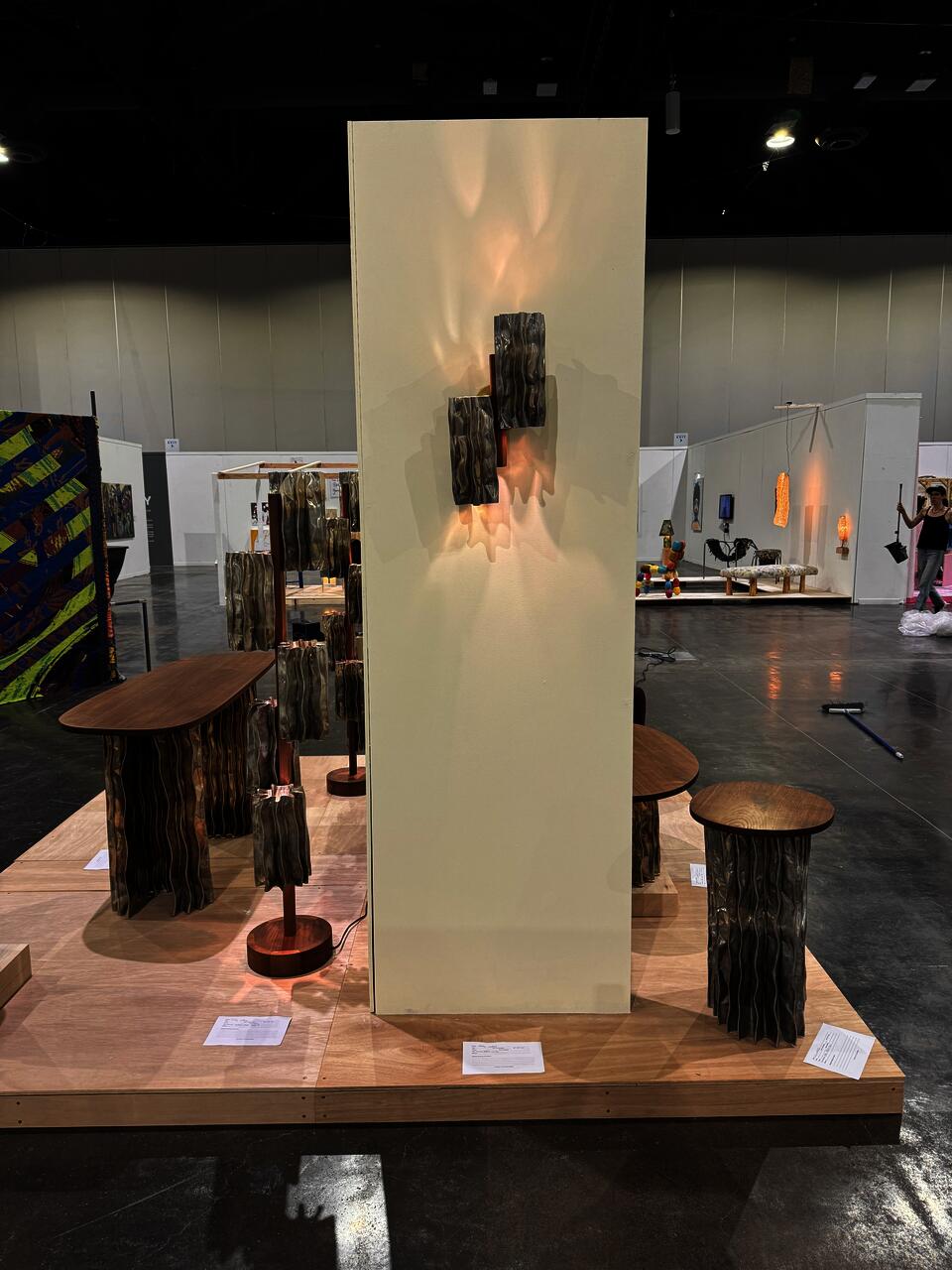 A modern furniture collection includes a coffee table, console table, pedestal table, and two floor lamps. The tables have an aluminum base and walnut tops. The floor lamps display decorative aluminum shades and central walnut stands.