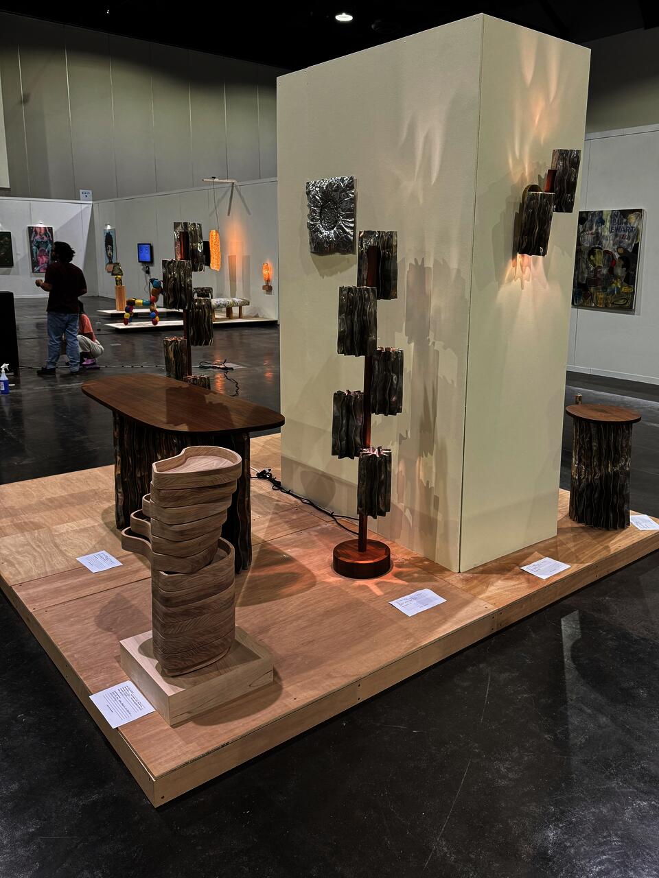 A modern furniture collection includes a coffee table, console table, pedestal table, and two floor lamps. The tables have an aluminum base and walnut tops. The floor lamps display decorative aluminum shades and central walnut stands.