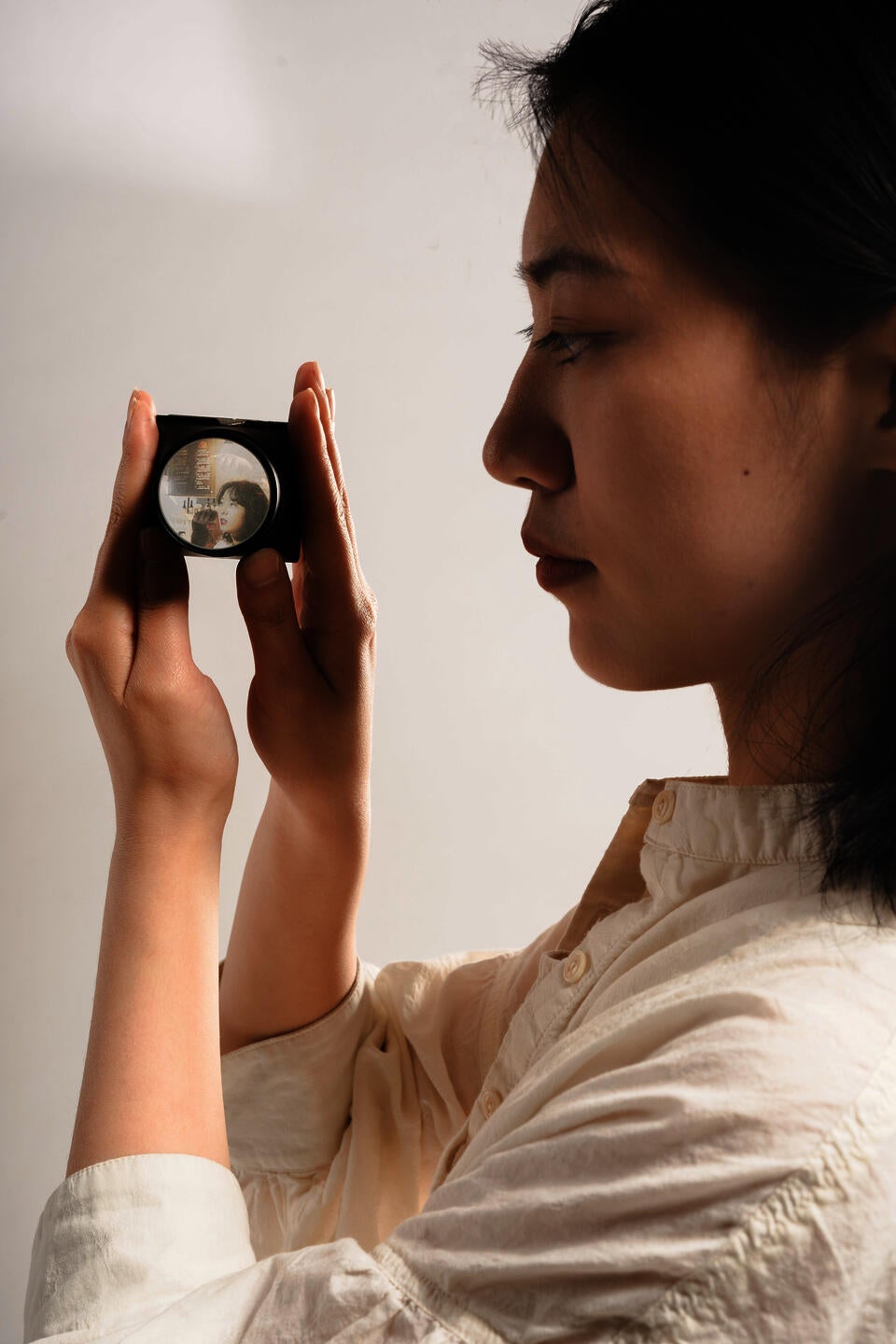 Through the lens that holding in the girls hand, a image of a woman is projecting.