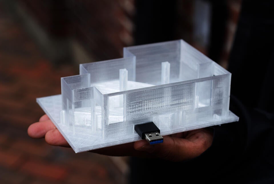 A 3D-printed model of a room with a USB stick mounted on the side of it.
