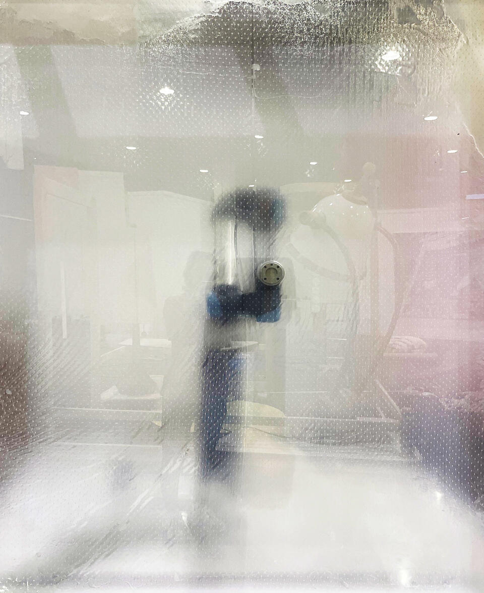 A robotic arm seen through a semi-translucent lacey membrane. 