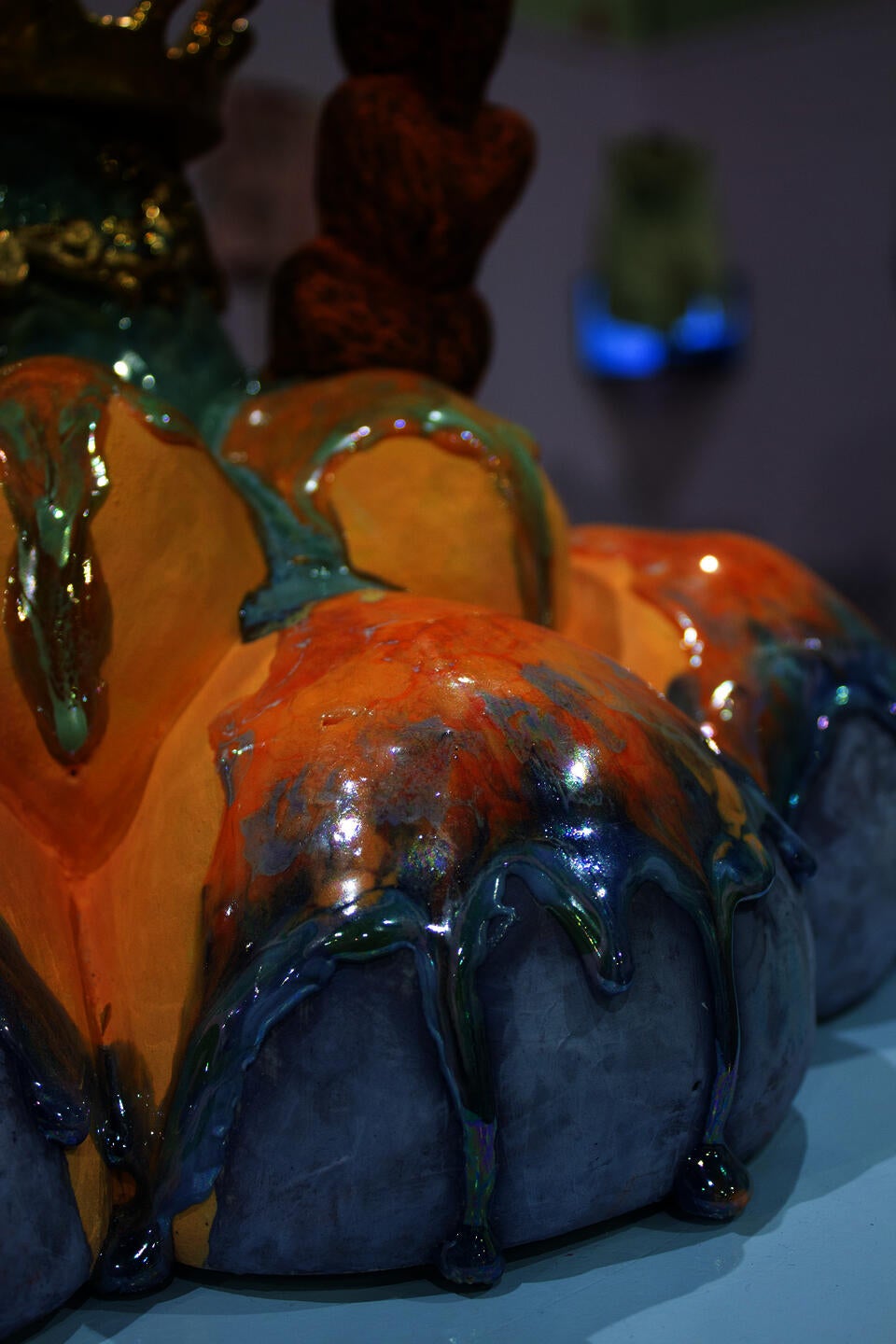 Close-up of a glossy ceramic flower sculpture with vibrant hues, featuring drip-like textures. 