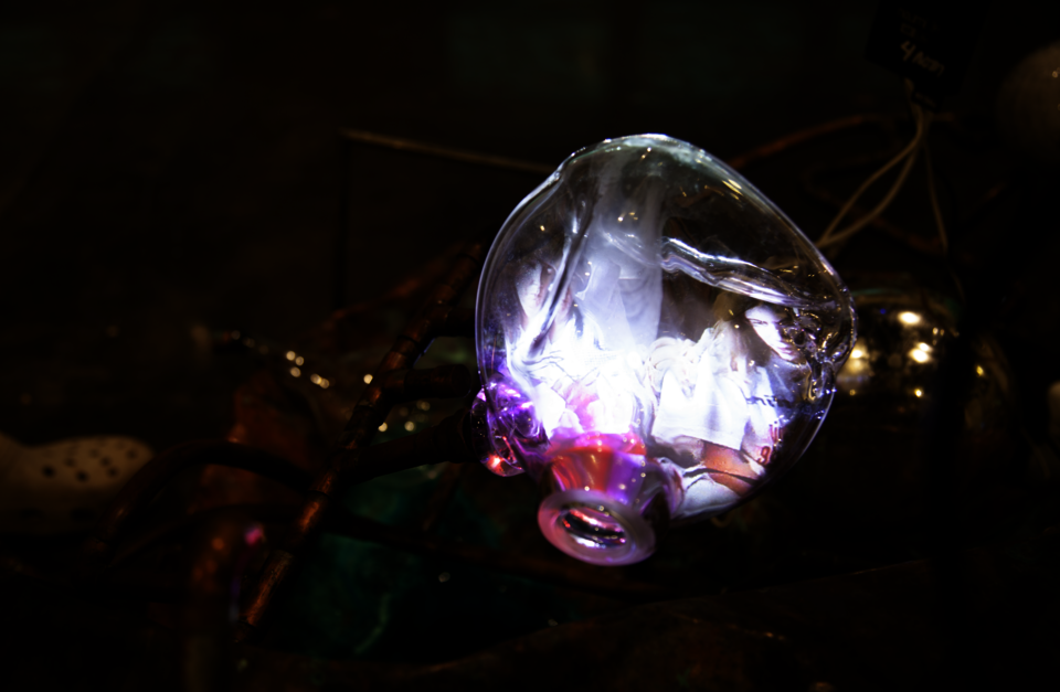 bright glass with abstract color glowing on it with copper pipes intertwined behind it. a green patina is on the copper as well