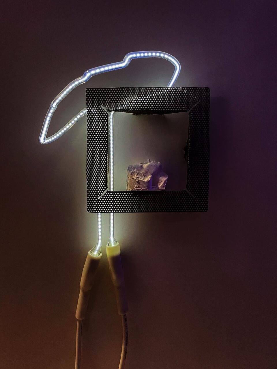 white silouette with a slight purple hue, facing upward within the frame of perferated steel, a squiggle of neon light in a white color with dotted pattern and wiring is to the left 