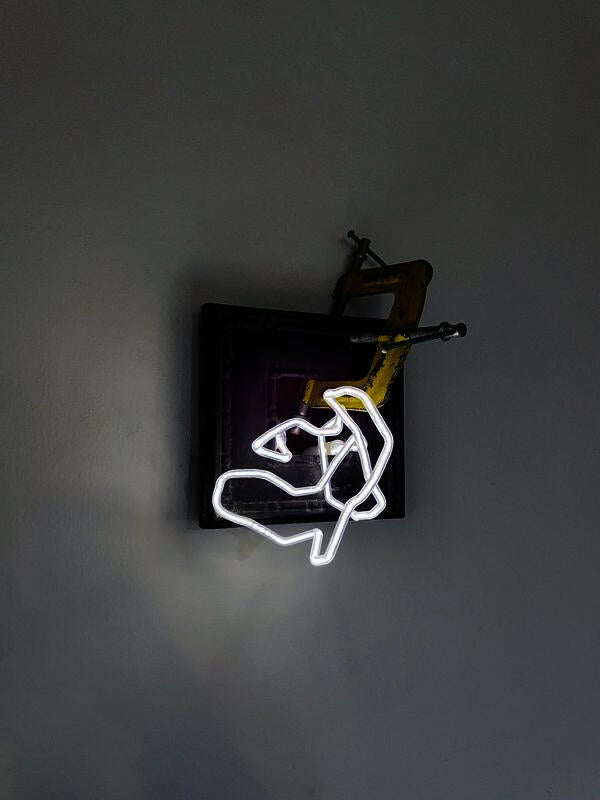 a yellow three way clamp attached to a wooden frame inset into the wall with a skinny white light squiggle coming out of it.