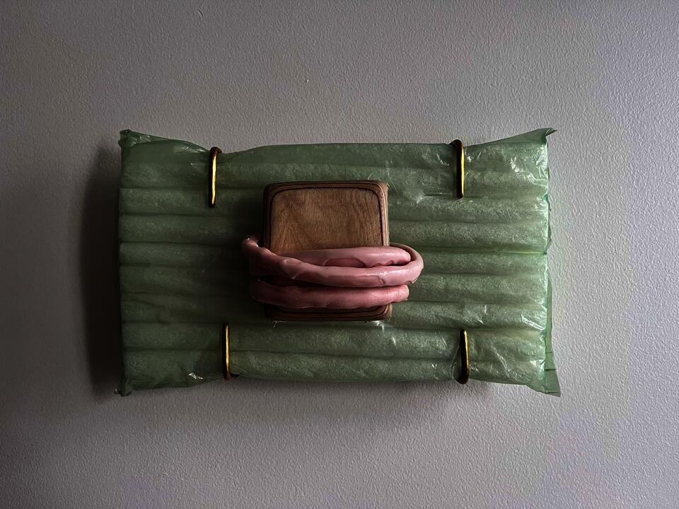 a yellow three way clamp attached to a wooden frame inset into the wall with a skinny white light squiggle coming out of it.