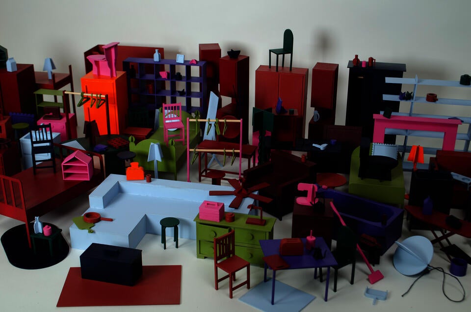 zoomed in, cropped, group photograph of all the everyday objects made at 1:12 scale. They are painted in a color palette of hot pink, deep red, orange, purple, navy, pale blue, dark green, and a deep chartreuse. 