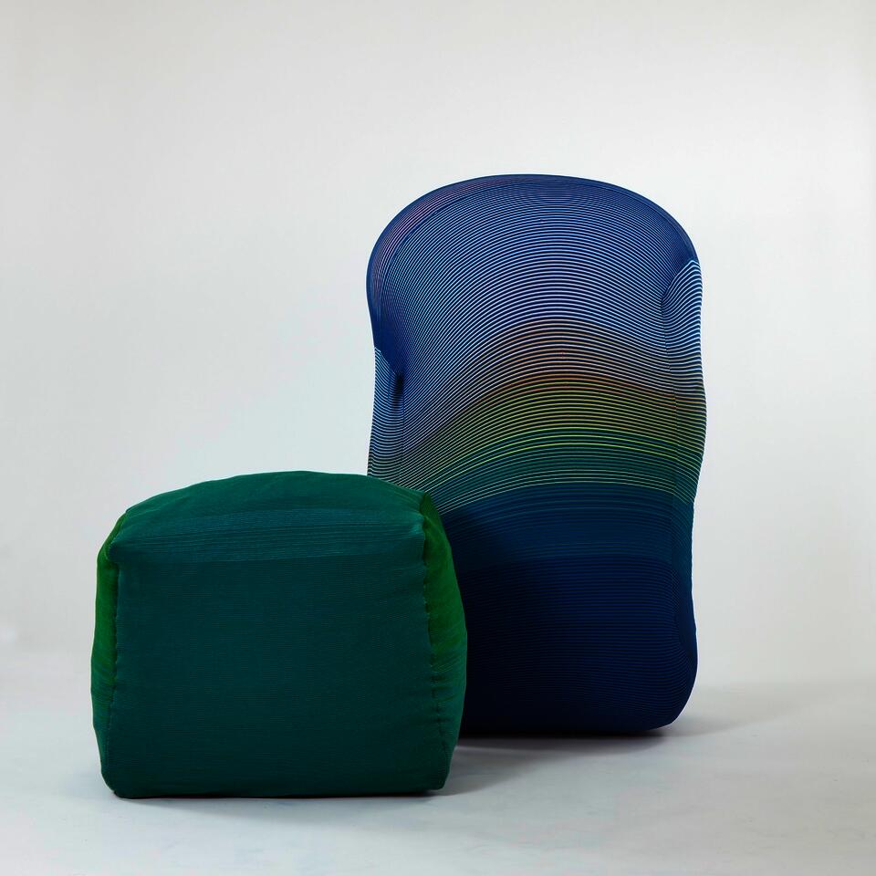A cushioned bench covered in green wool knit sits on the left side. A blue inflated Knit Wiggle wall sits next to it.