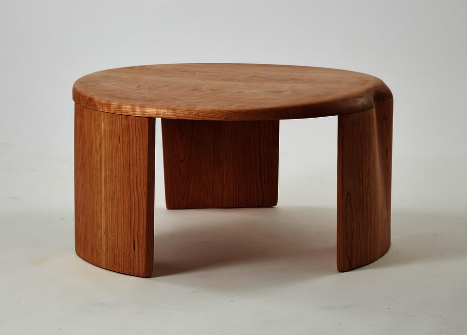 This is a coffee table consisting of three legs and a tabletop. Both the tabletop and the legs are joined together with a slight curvature.