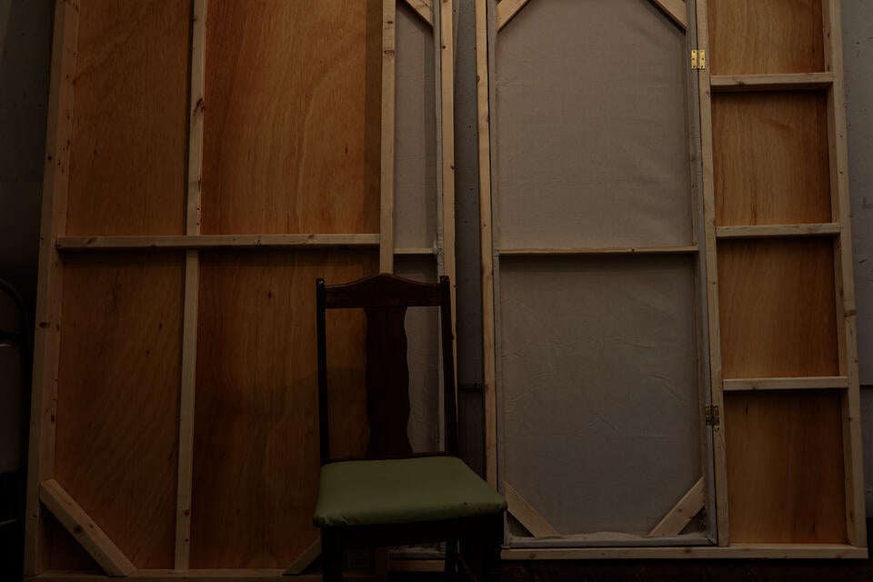 Image of deconstructed walls that make up the thesis booth - made of wood and cloth, with a wooden chair in front