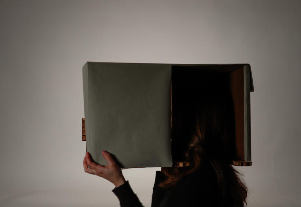 Woman holding cardboard video-projection box over her head