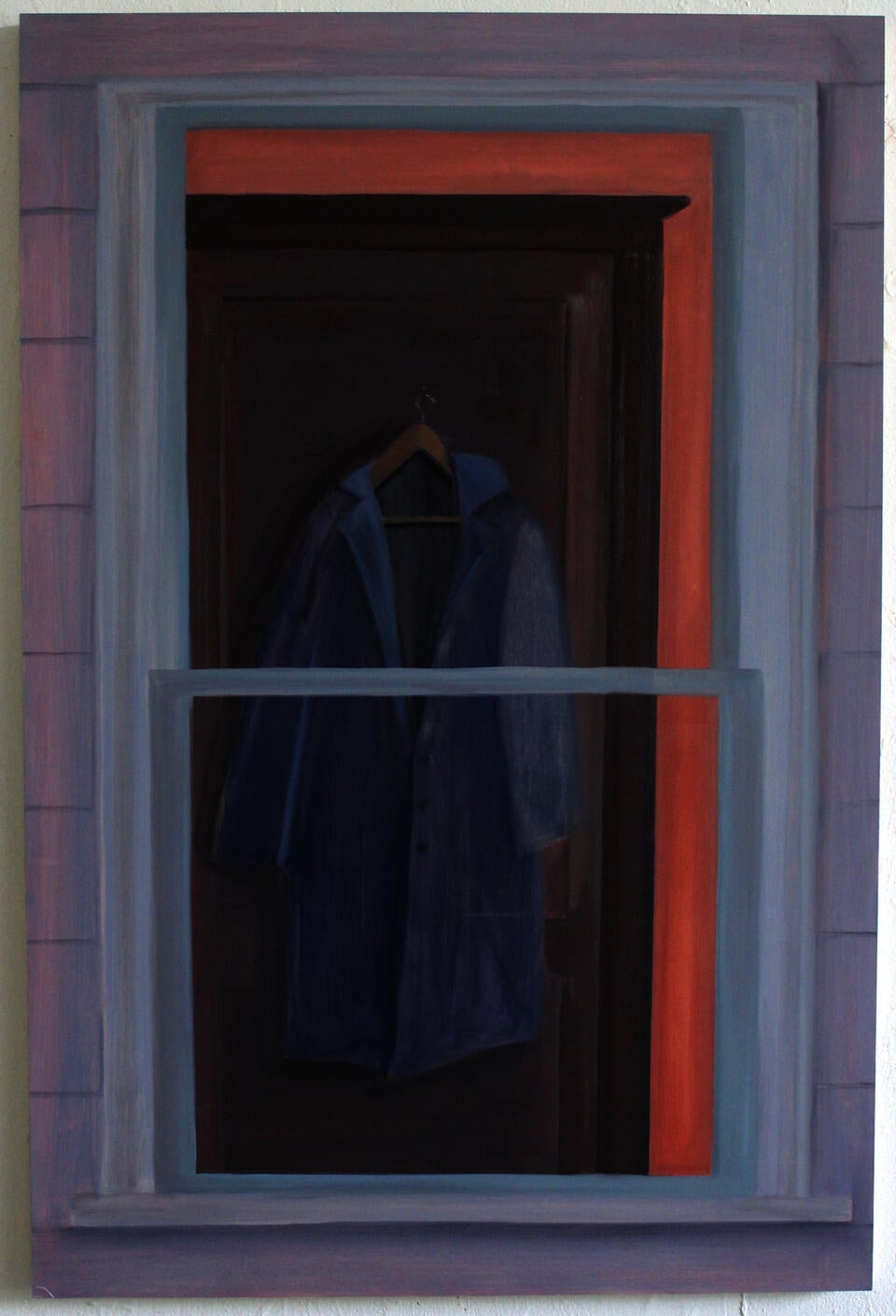 A coat hangs on a door, seen through a window.