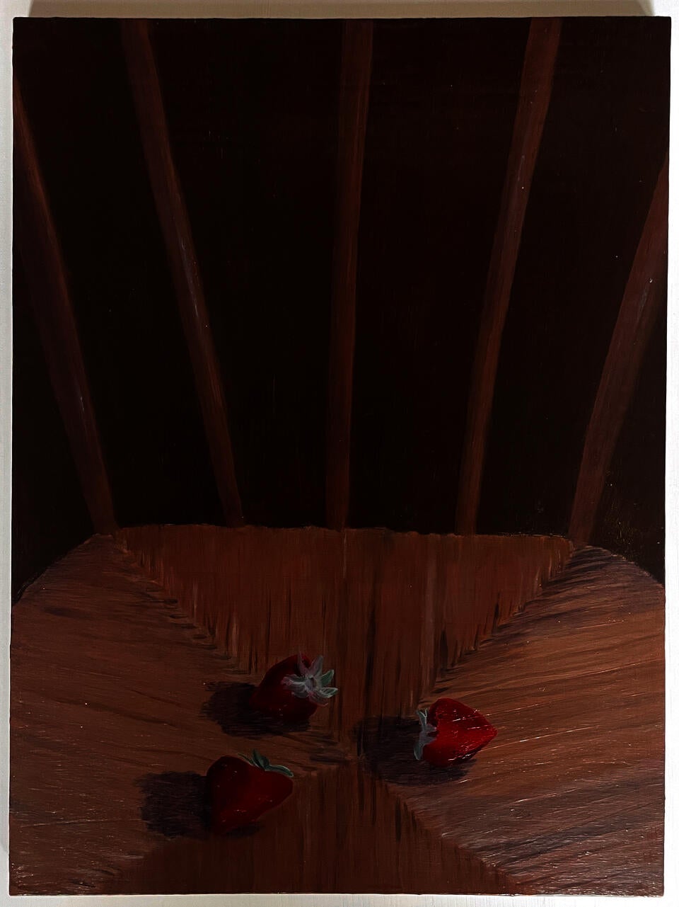 Three strawberries sit on a wicker chair.