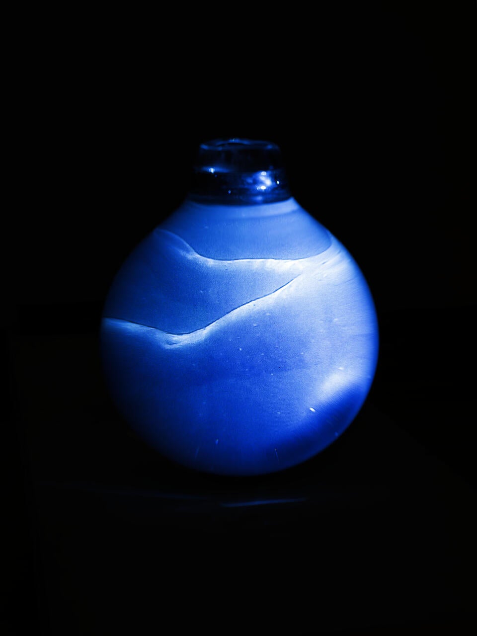 Image of a glass orb with blue light, water and a blurry figure
