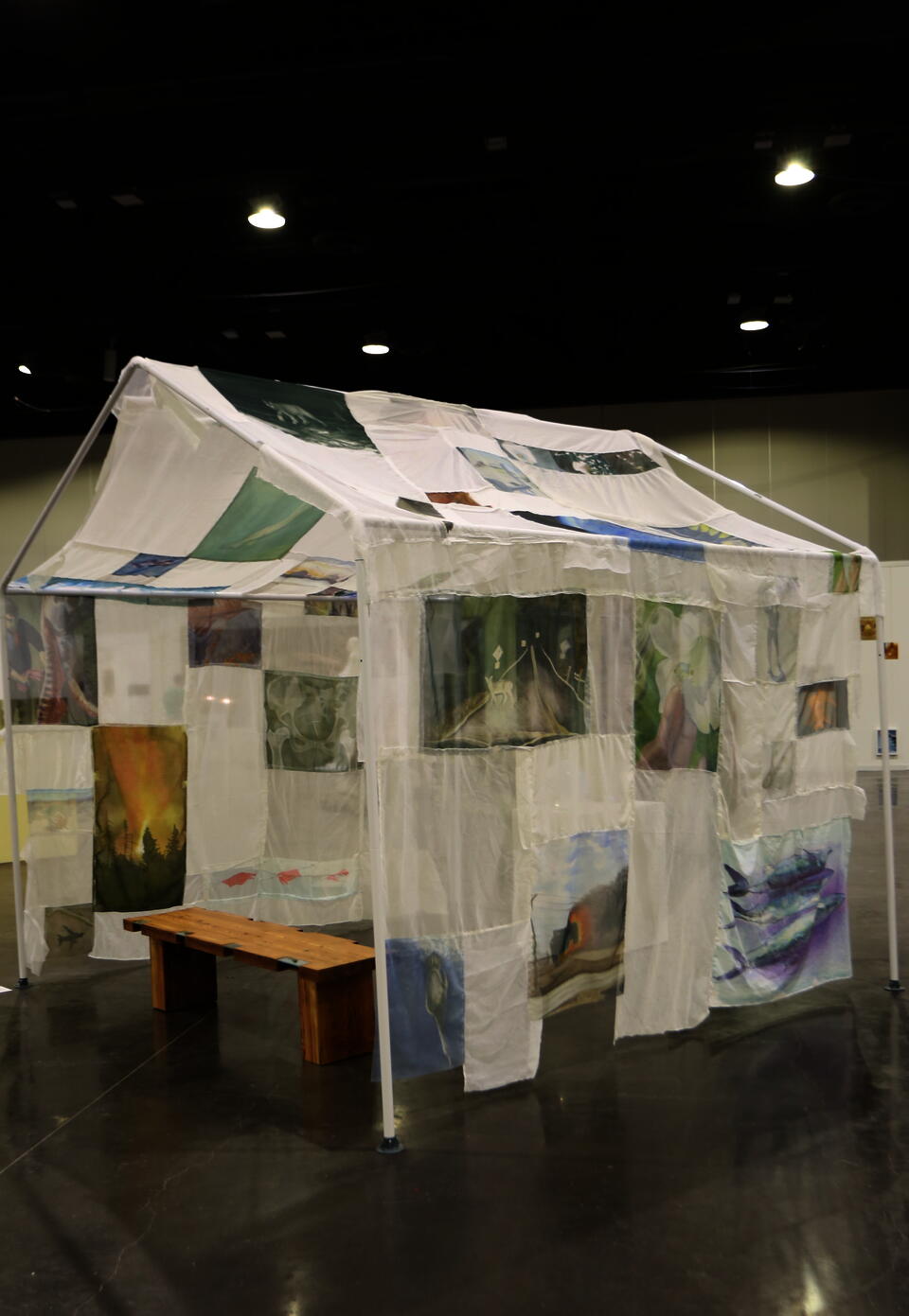 Paintings on transparent fabric draped over house frame 