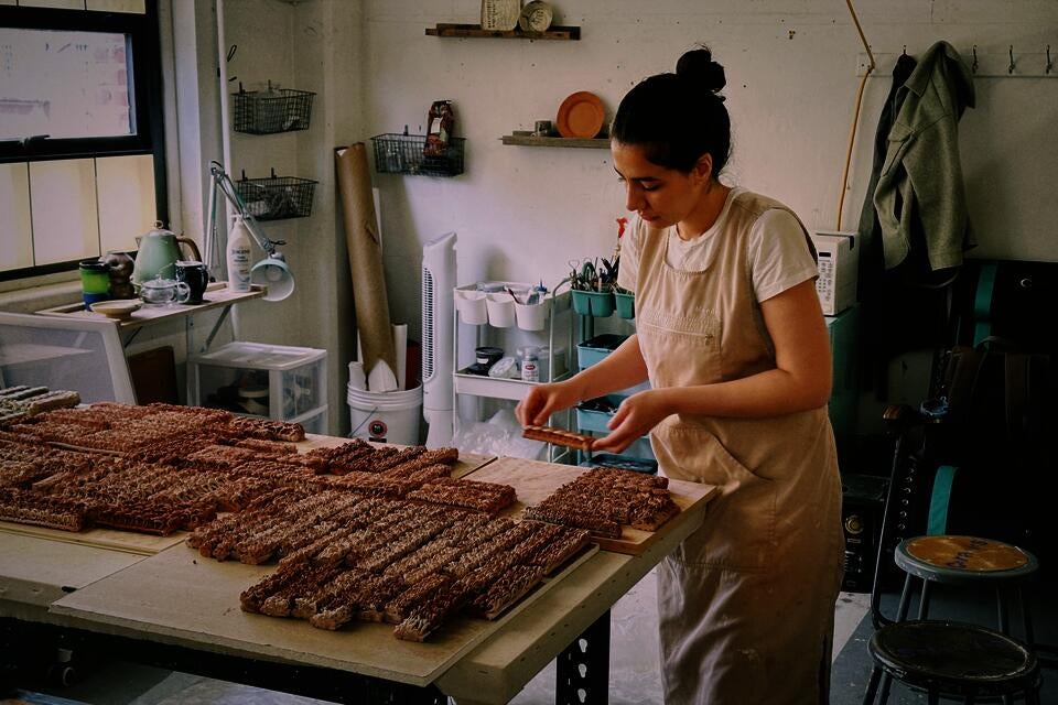 Artist arranging clay pieces on a table in a well-lit studio, surrounded by tools and materials, creating an organized and creative workspace