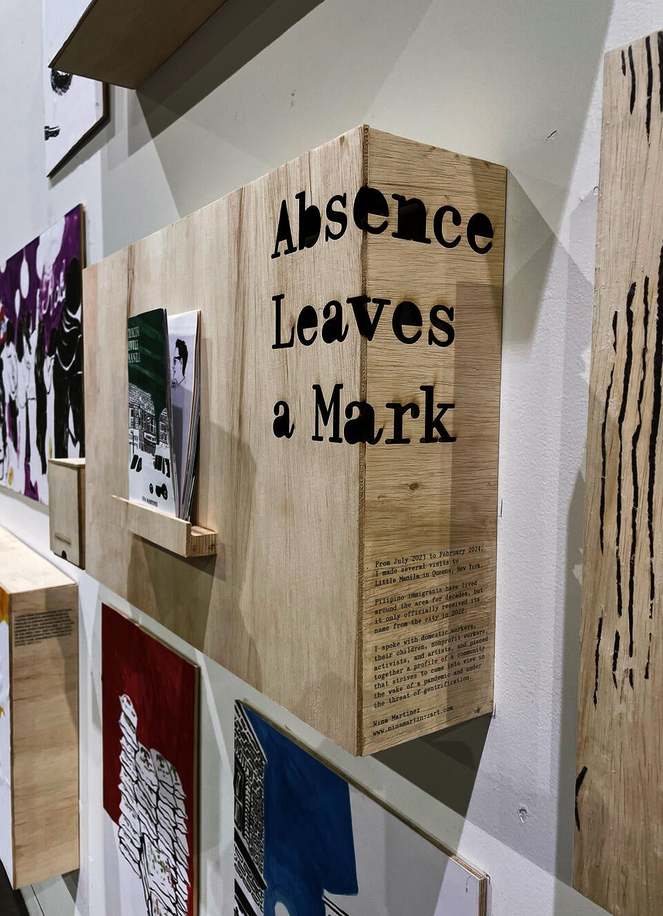 A detail shot of the corner of the plywood display, showing the thesis title Absence Leaves a Mark, plus a short description of my project created with gel transfer.