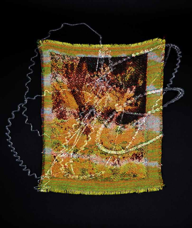 A small-scale yellow abstract weaving placed on a black background with a thin and swirly glass layer on top.