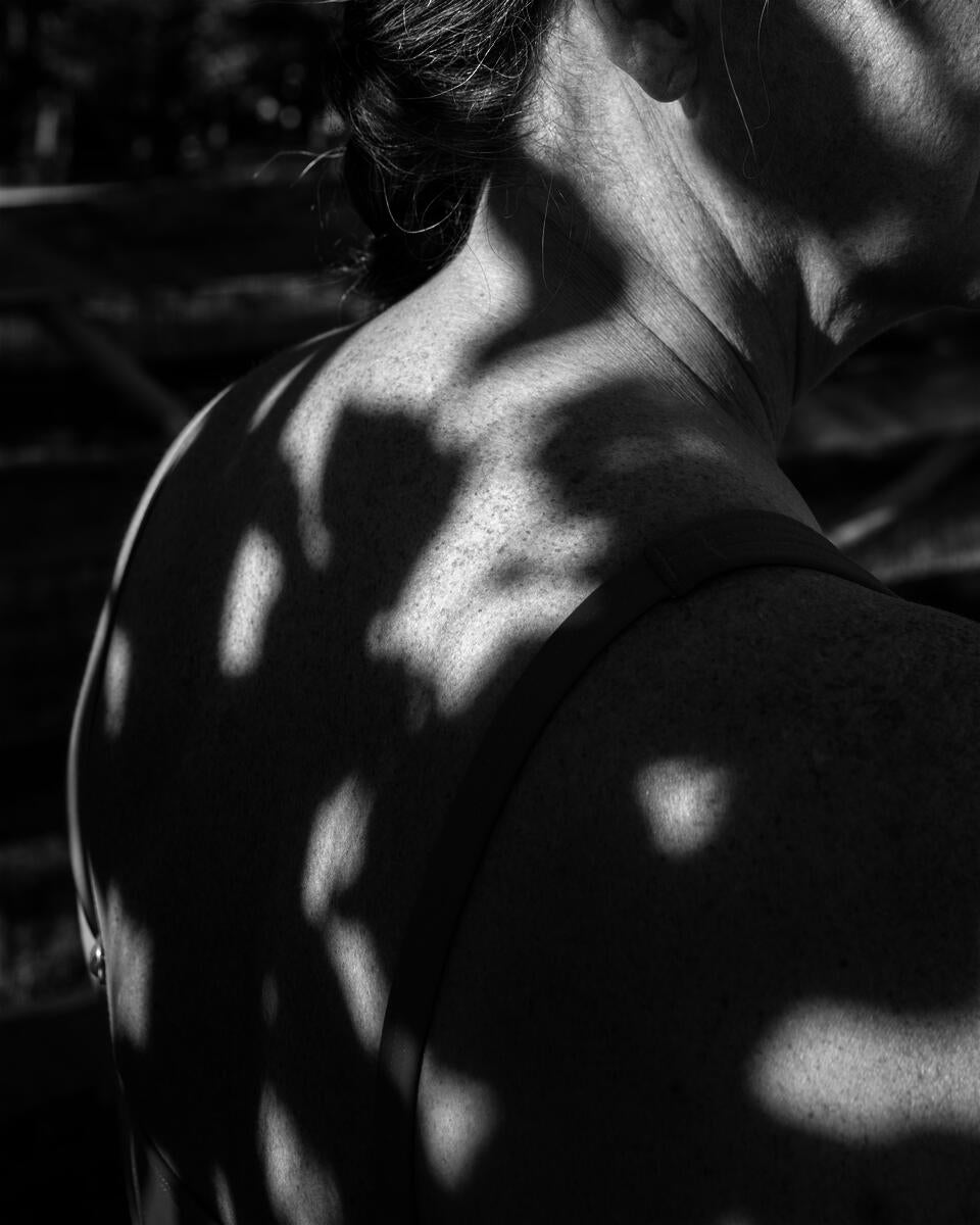 shadows from a nearby tree projected onto the back of a woman in her mid-50's.