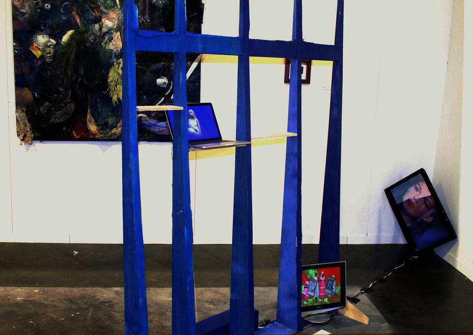 A large blue gate-like structure with shelves stands center. Untitled (Blue Portrait) is on the left shelf, DARKMAGICIANGIRL on the right. P.A.I.N. is on a screen in the right corner. STREETHTRASH and Highest Heaven, Deepest Hell are on the back wall.