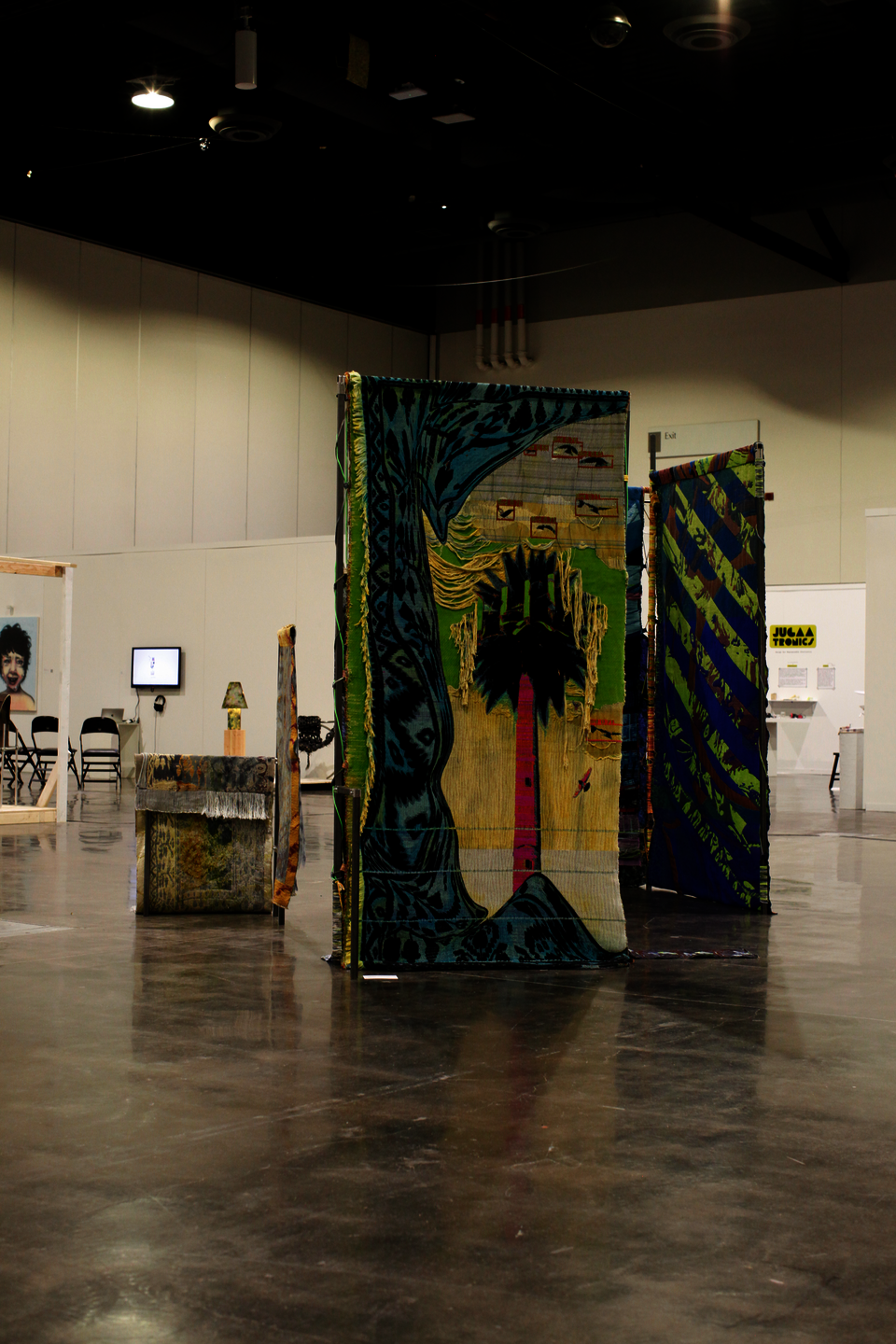 Large scale installation of metal steel frames with colorfull weavings standing in the middle of the floor at the convention center.