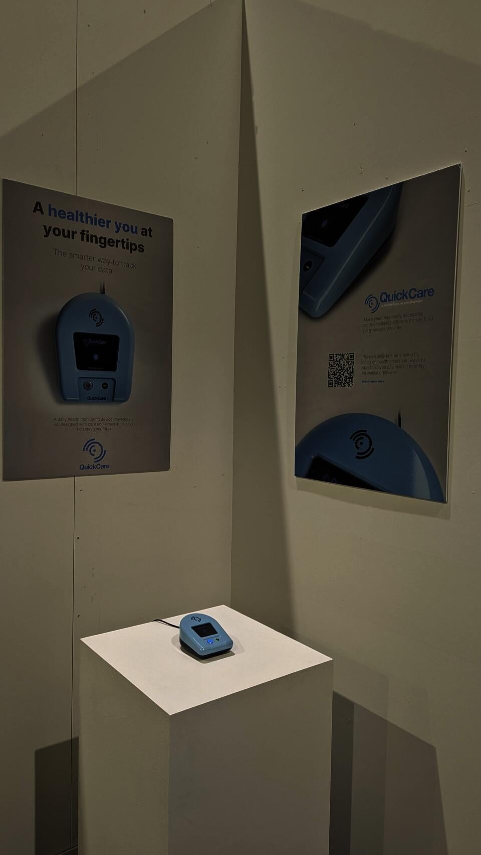 QuickCare product on pedestal placed in a corner between two promotional product posters. One poster has a QR that leads to an online product page.