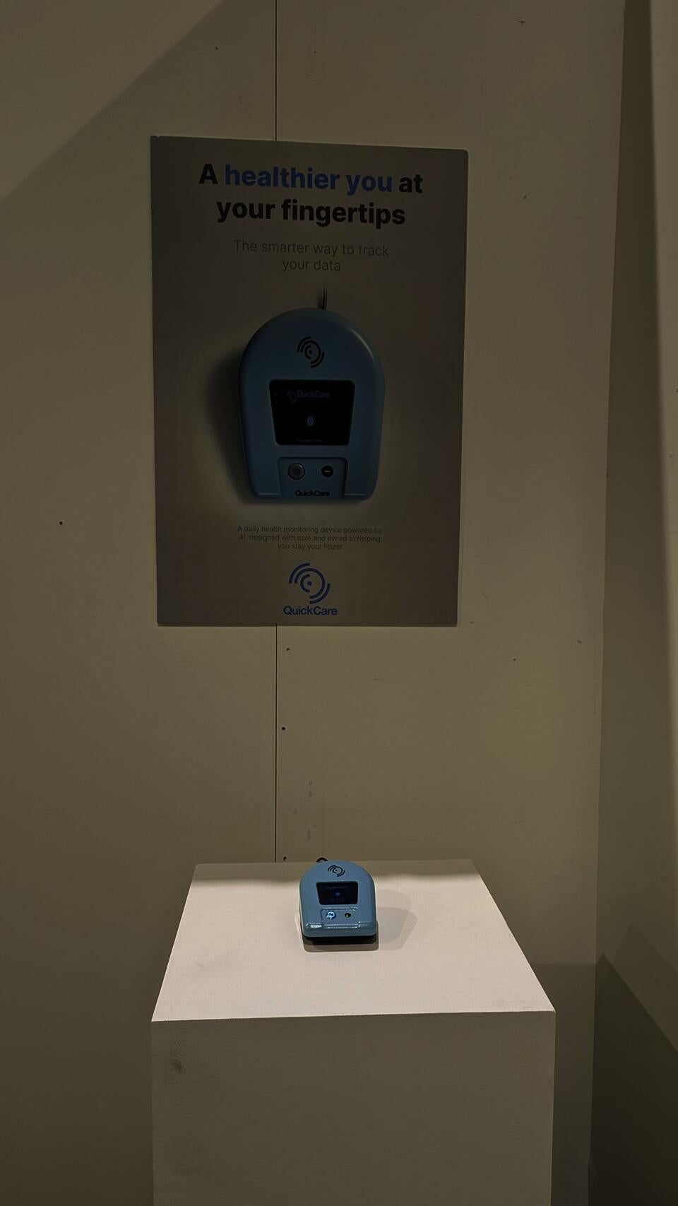 QuickCare product on pedestal placed in a corner between two promotional product posters. One poster has a QR that leads to an online product page.
