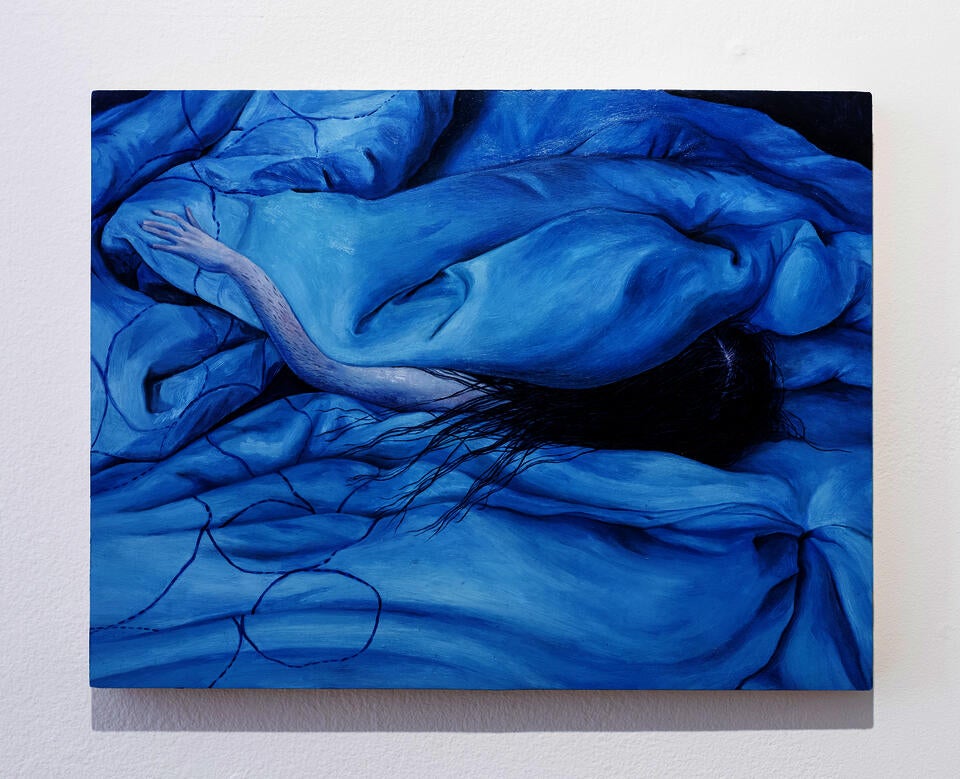 A human arm and head with long black hair pokes out of a blue duvet blanket that takes up the entire composition