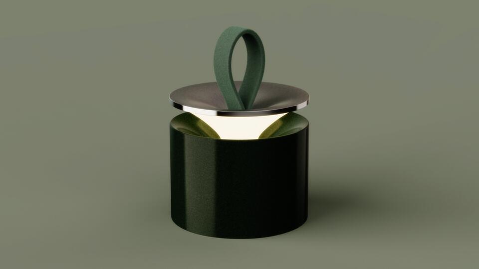 A glossy green ceramic lamp with a soft felt loop handle and lifted metal lid, glowing warmly from within.