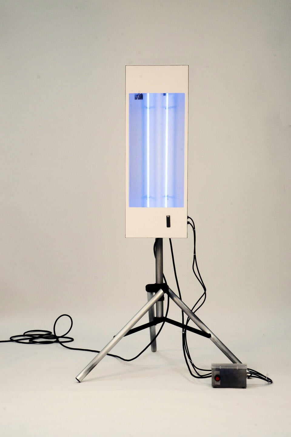 White box mounted on aluminum tripod with two blue neon tubes inside