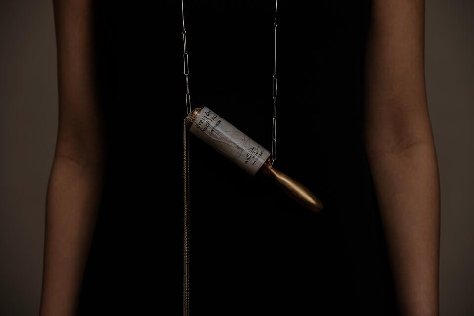 Necklace with metal lint roller pendant; segments tear off as individual pieces, titled and packaged “Everyday Necklace.”
