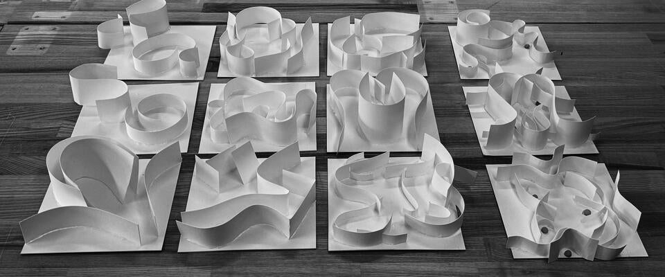 Twelve white paper models transform chair elements into abstract forms exploring space and movement