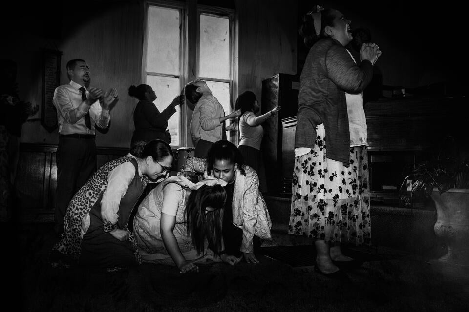 A ribbon in her hair, she falls weeping, held by sun; a procession of worshippers turn faces to God, a click, a pop of light.