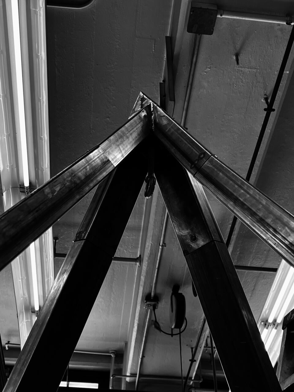 The apex of a pyramid shaped steel structure, with a forged eyebolt welded at the center