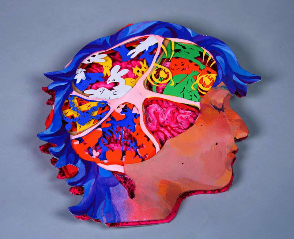 Tunnel book made with, museum board, paper, gouache, acrylic, air dry clay, glitter, glue and gloss finish. Book shaped of a face side profile, where the brain should be is an opening with 5 sections. 1 of a brain, one of bunny like creatures, one with memories locked away and one of love. 