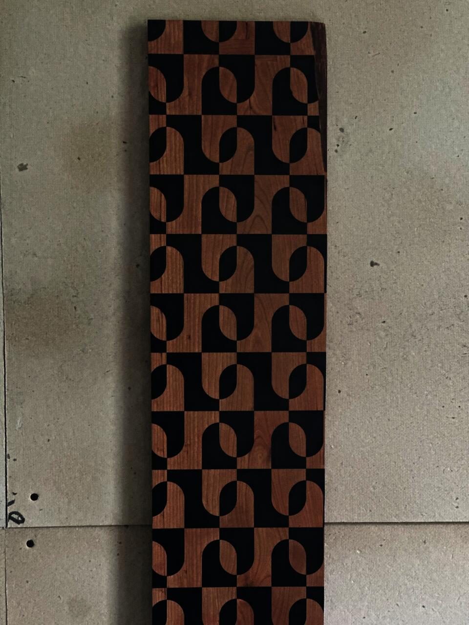 Cherry wood growth chart with a geometric pattern created through masked black vinyl mounted to the wood. 