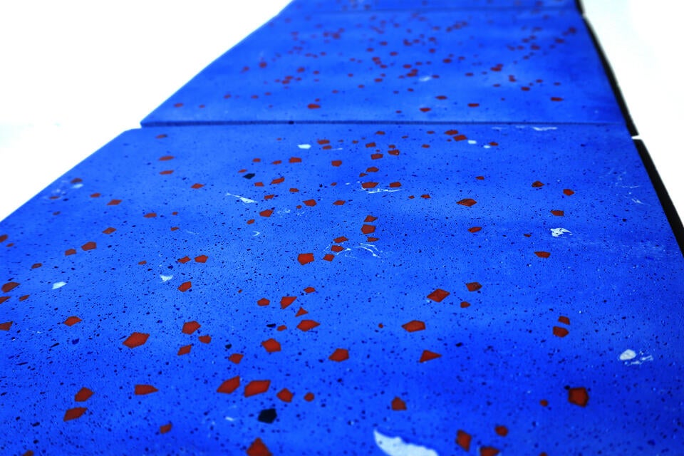 Pale blue terrazzo tiles with scattered geometric fragments seen from a low angle, receding into the distance.
