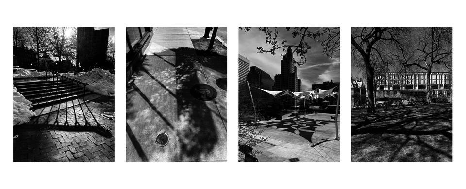 4 photos of natural, architectural, or mixed shadows: long shadow from steel railing; reflected light and sidewalk tree; geometric shadows from tension fabric roof; shadow of spread branches from old trees on a grass field.