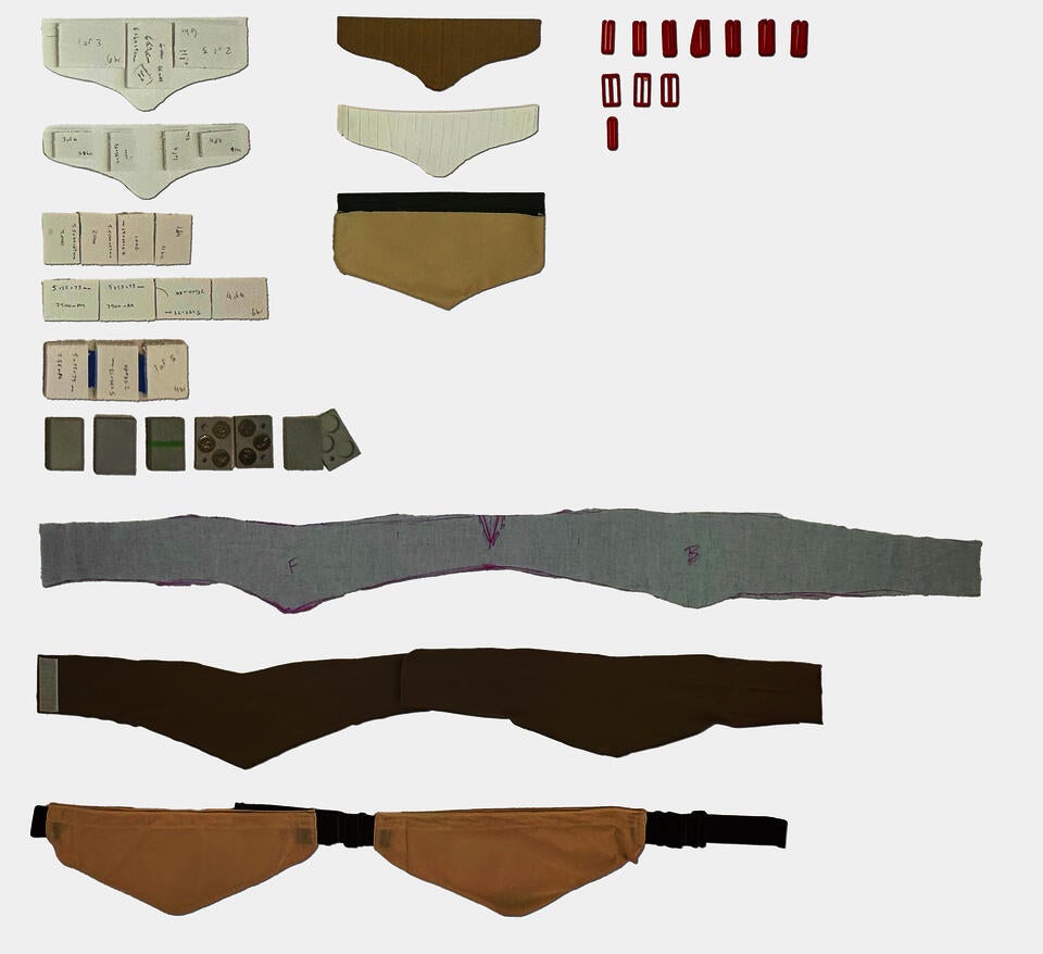 A flatlay of prototypes in process, including clips, fabric belts, and simulated batteries