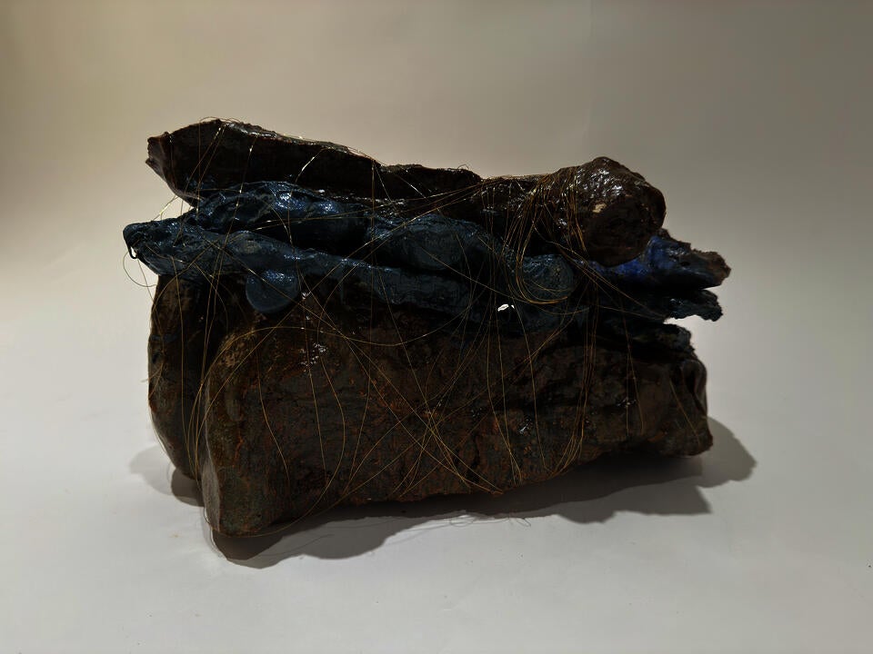 Three large smooth shiny glazed rock like pieces are faceted together with purple rubber.  The entire piece is wrapped with small copper thread as thin a hair.