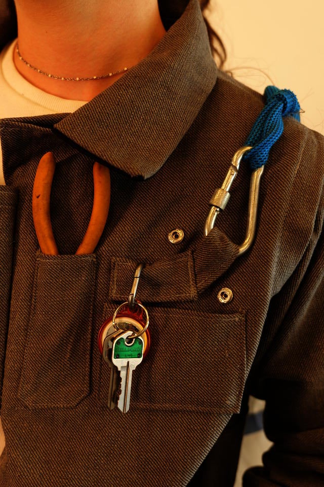 A close up shot of front upper pockets on a gray canvas jacket. These pockets house ID's, keys, yellow tools, and snap closed.